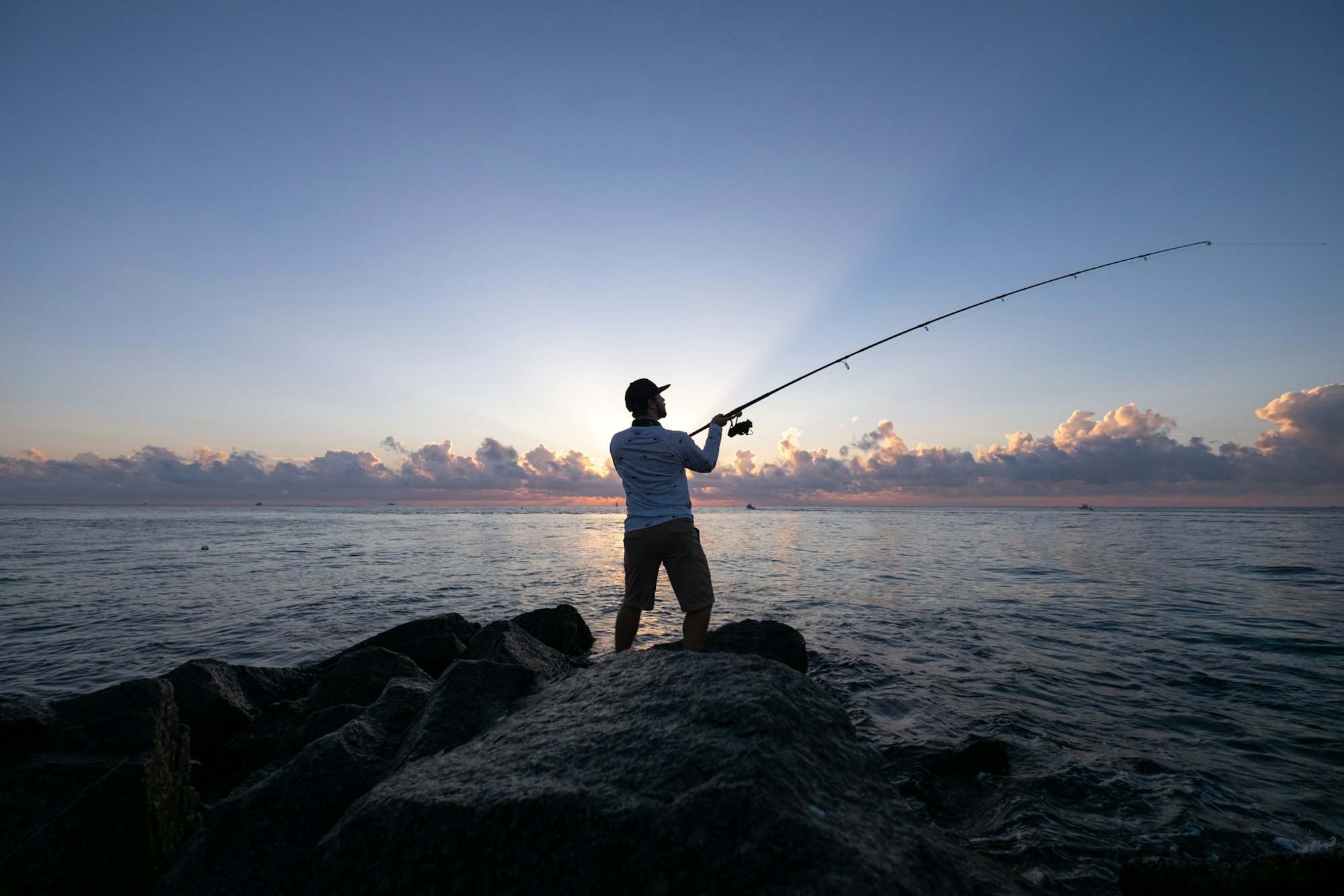 Angler casting from rocks at dawn